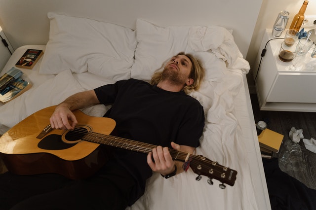 Sad guitarist on bed with the minor scale