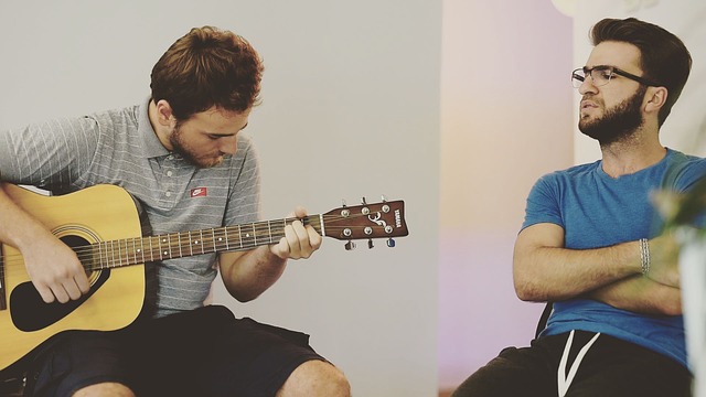Friend teaching how to play beginner guitar